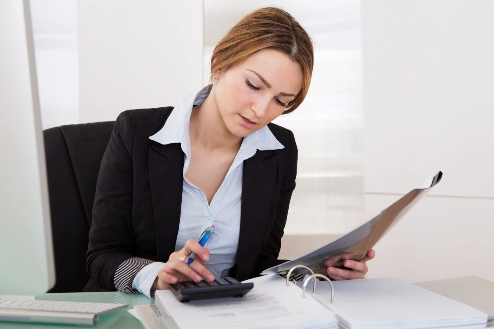 A woman sitting at her desk with papers and a calculator.