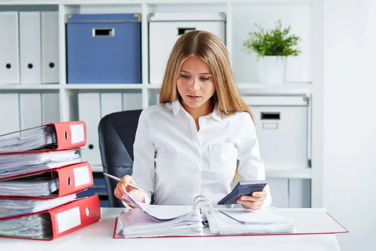 A woman sitting at her desk with papers and cell phones.