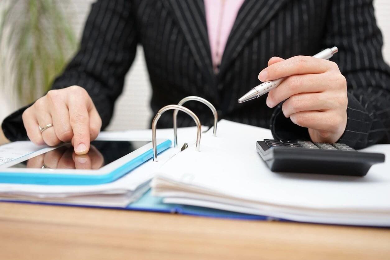 A person sitting at a table with papers and a calculator.