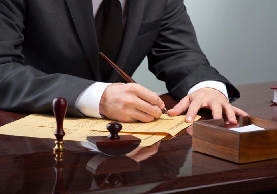 A man in suit and tie writing on paper.